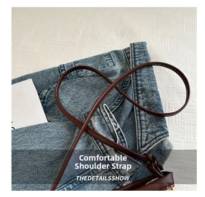 Close-up of brown leather shoulder strap with knot detail on denim background