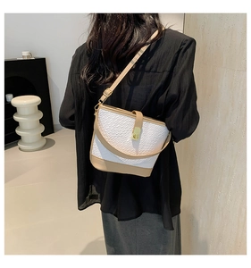 Detailed view of woven texture bucket bag with contrast leather and gold swivel lock