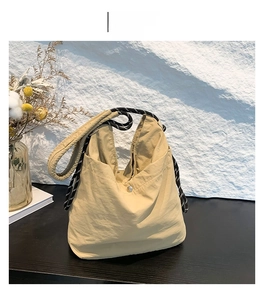 Detail view of khaki nylon tote bag featuring rope strap and silver magnetic snap closure