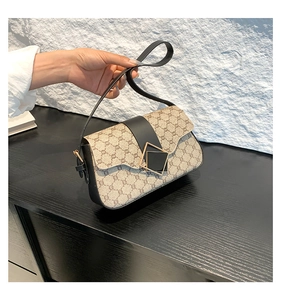Détail du sac sous l'aisselle beige vintage avec rabat en cuir noir et boucle dorée