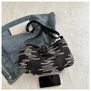 Detail of black canvas dumpling bag with colorful wave embroidery on denim jacket