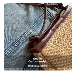 Detailed close-up of handmade woven straw bucket bag with dark brown leather trim and knotted strap