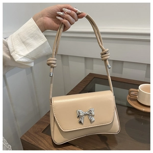 Détail du sac beige minimaliste avec nœud argenté et bandoulière à nœud décoratif