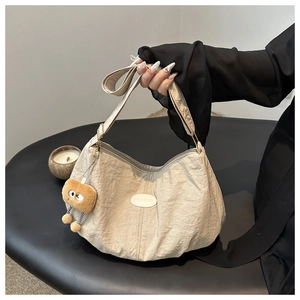 Detail of beige pleated shoulder bag with fashion patch and plush toast pendant charm