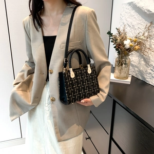Elegant black tweed lady bag with gold accents and woven leather handle in a lifestyle setting