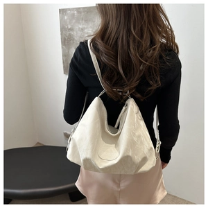 Detailed close-up of cream white hobo bag showing crinkle texture and logo emblem