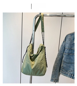 Detail of green nylon hobo bag with black and white rope strap and silver magnetic buckle