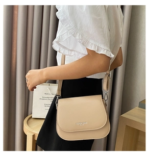 Detail of beige saddle bag with adjustable wide strap and silver metal hardware