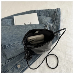 Détails de la pochette téléphone en cuir noir brillant montrant l'intérieur et le fermoir