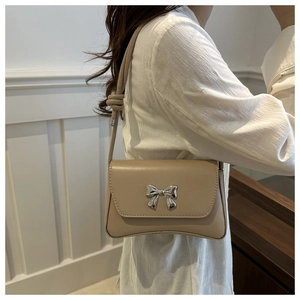 Détail du sac baguette beige avec nœud métallique argenté et bandoulière nouée