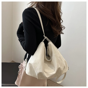Close-up of cream pleated shoulder bag showing unique ruched texture and silver hardware