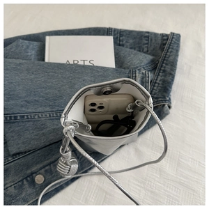 Détail d'un sac bandoulière argenté pour téléphone avec fermeture magnétique et espace lunettes