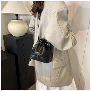 Detail shot of a black drawstring bucket bag with heart motif on a stylish blazer outfit