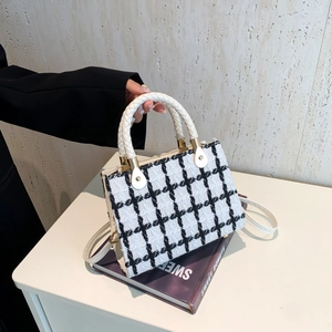 Classic black and white tweed crossbody bag with woven handle and gold hardware detail