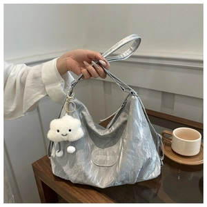 Detail of silver pleated shoulder bag with adjustable strap and white cloud charm accessory