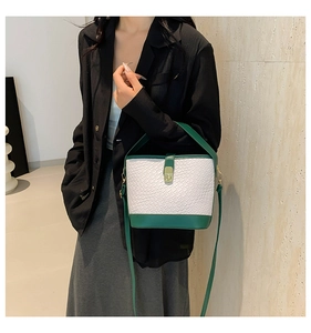Detail of green woven bucket bag showing metal twist lock and adjustable shoulder strap