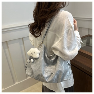 Silver wrinkled hobo bag with cloud plush charm shown on person in a bright setting
