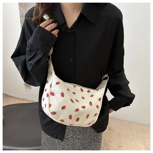 Detail of a beige corduroy crossbody bag featuring a cute red strawberry print pattern