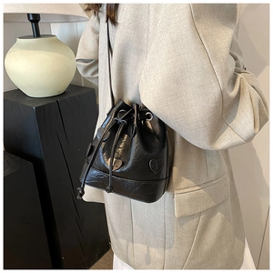 Detail shot of black drawstring bucket bag featuring embossed textures and heart-shaped patch