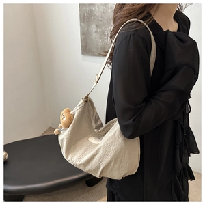 Detail of off-white nylon tote bag with fashion label and brown teddy bear charm