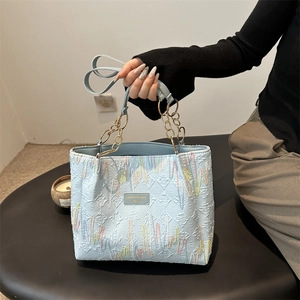 Sac cabas bleu clair matelassé avec broderies colorées et détails de chaîne dorée