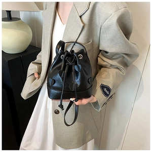 Detail view of black drawstring bucket bag featuring 3D heart patches and sleek leather