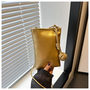 Détail du mini sac en cuir doré métallisé avec breloque boule tissée et bandoulière