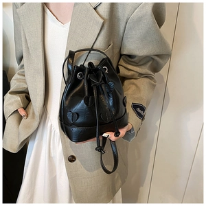 Detail of black drawstring bucket bag featuring heart leather patches and top handle