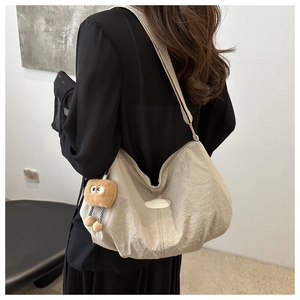 Detail of beige pleated shoulder bag with fashion logo and brown plush charm