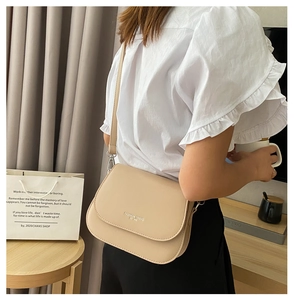 Detailed view of beige saddle bag with Fashion Trend logo worn by model on shoulder