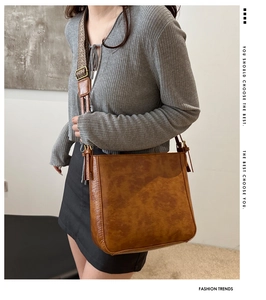 Detail of vintage brown leather tote bag featuring ethnic style woven wide shoulder strap