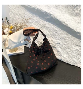Dettaglio borsa tote in velluto nero con ricamo di fragole e chiusura a coulisse