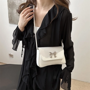 Sac à bandoulière blanc brillant avec nœud argenté porté par un mannequin de profil