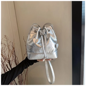 Detail of silver pleated bucket bag featuring metallic heart patches and drawstring closure