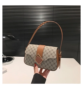Détail du tissu à logo imbriqué et des finitions en cuir marron du sac porté épaule