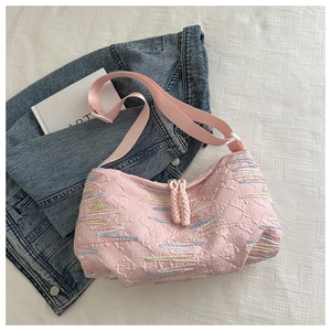 Detail of pink quilted dumpling bag with embroidered wave patterns and wide strap