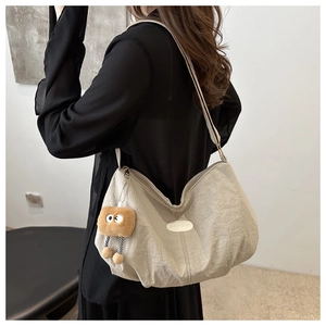 Detail of light beige tote bag with natural texture fabric and cute toast pendant