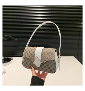Détail du sac vintage avec toile monogrammée et fermoir métallique carré doré sur le rabat