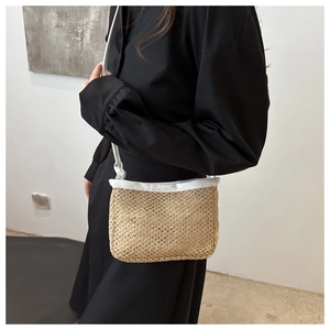 Detail of hand-woven straw crossbody bag featuring white trim and elegant thin strap