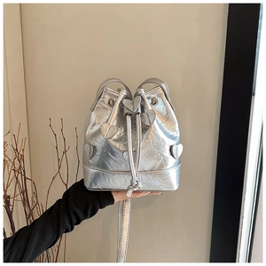 Close-up of silver drawstring bucket bag with metallic pleated texture and heart patches