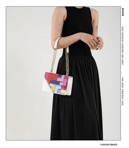 Détail du sac à bandoulière aux motifs géométriques colorés avec chaîne dorée sur mannequin