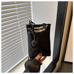 Détail d'un mini sac de téléphone noir brillant avec bandoulière à nœud unique