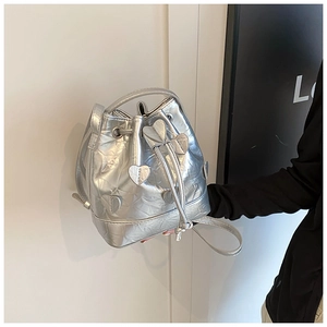 Detail view of silver drawstring bucket bag with heart appliques and adjustable strap