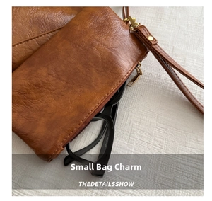 Close-up of brown PU leather pouch with vintage lychee texture and wrist strap