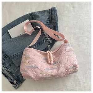 Detail showing pink quilted fabric textures and colorful embroidered lines on the shoulder bag