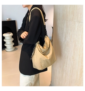 Detail of beige nylon shoulder bag with woven rope accent on a professional model
