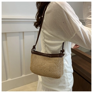 Detail of vintage straw bucket bag with dark brown leather trim and knotted shoulder strap