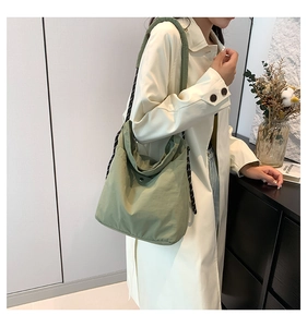 Detail of avocado green nylon tote bag featuring a woven strap and metal snap closure