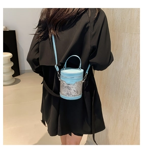 Close-up of light blue cylinder bucket bag with white embroidery and lace details