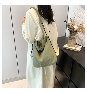 Detail of light green nylon tote bag featuring durable black and white rope shoulder straps